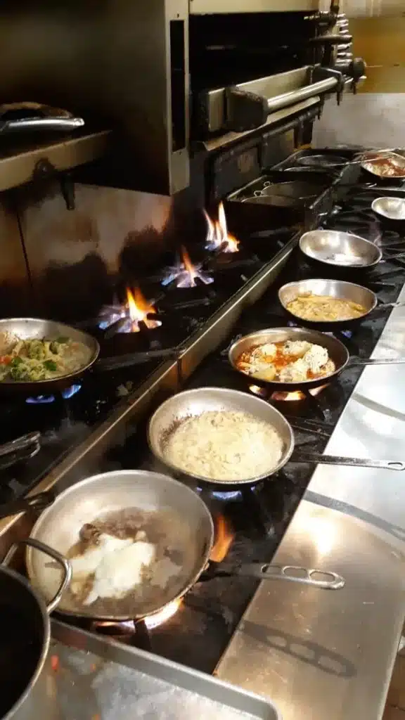 A bunch of saute pans on a bunch of burners